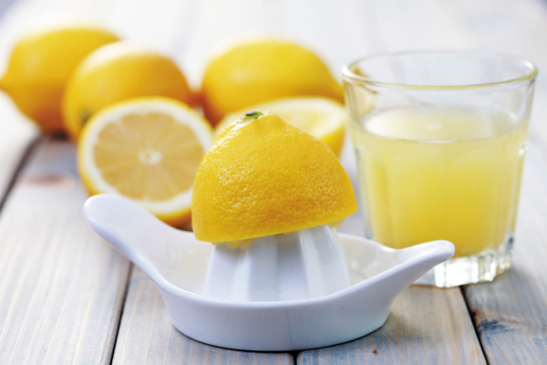 Лимоны, ручная соковыжималка и стакан с соком